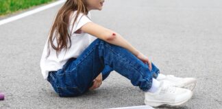 An image of a young girl with blood on her arm and a scooter on the ground nearby.