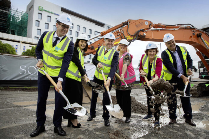 Dignitaries and stakeholders pose with shovels at the site of SOL by Walker.