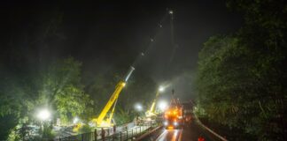Cranes are used to put a bridge into place at night.