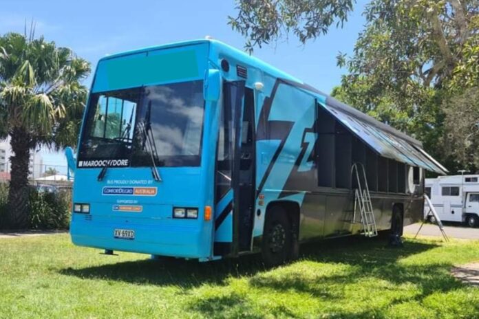 A bright blue bus that opens at the side to allow people to sleep in it.
