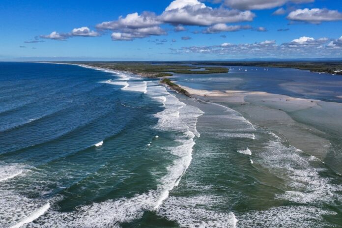 An aerial photo shows waves rolling through the Bribie Island breakthrough, which is more than 1km wide. Picture via Bluey's Photography.
