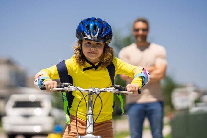 A father watches his son ride down the street. Picture by Shutterstock.