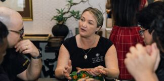 Silver Seas Seafood managing director Jacky Cartwright speaks at a table, while eating fresh seafood.