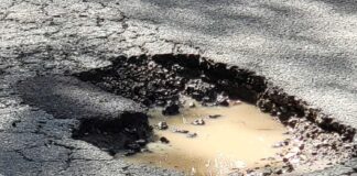 A large pothole with muddy water in it.