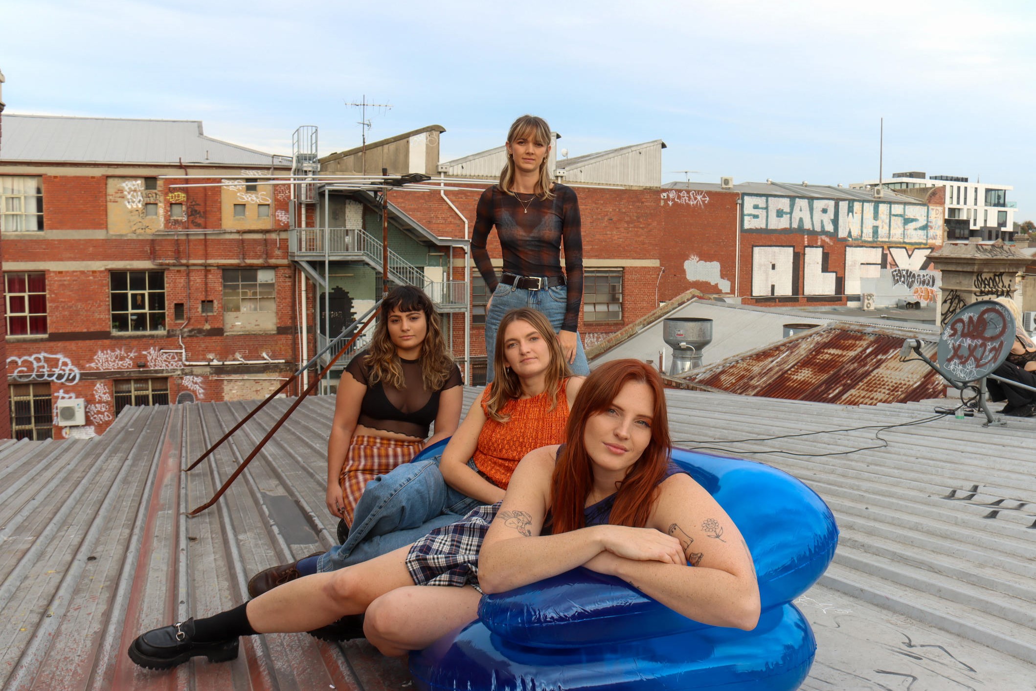 Indie pop group Betty Taylor members lounge around on the roof of a building.