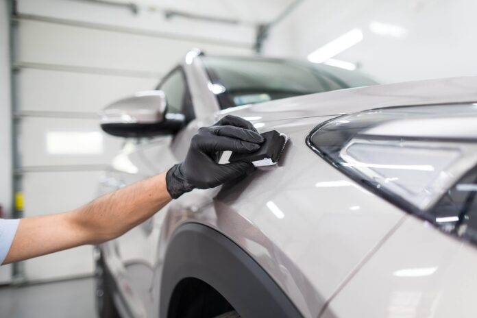 A man applying protective coating to a car.