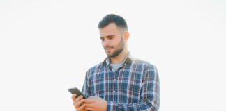 A farmer in an agricultural field holding a phone.