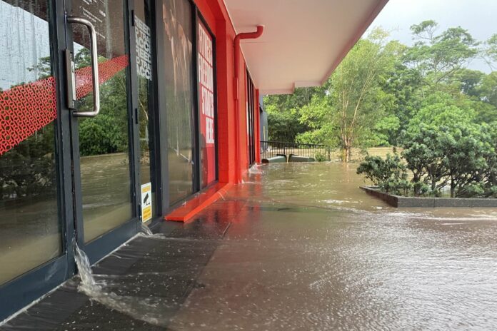 Water gushes out of the doorways of the Jetts gym at Nambour in early March. Picture: Steele Taylor.