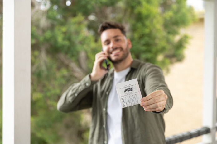 A man shows his Saturday Gold Lotto ticket while he talks on the phone.