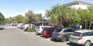 Cars parked outside shops along a Peregian Beach street.