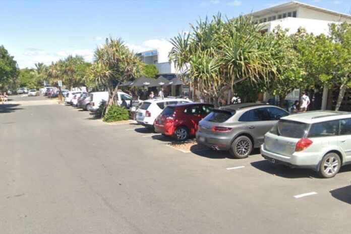 Cars parked outside shops along a Peregian Beach street.