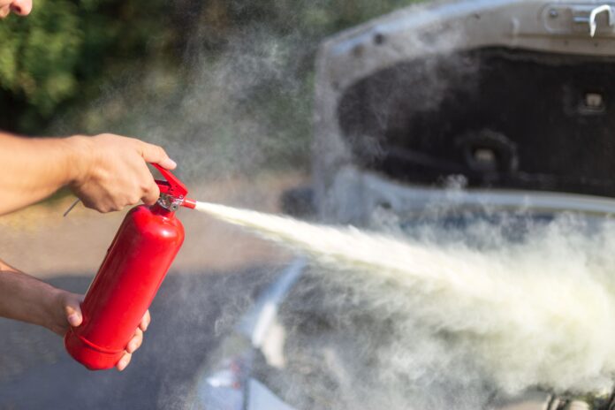A man spraying a fire extinguisher at a car