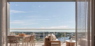 A luxurious apartment balcony with outdoor dining and lounge suite overlooking the Pumicestone Passage.