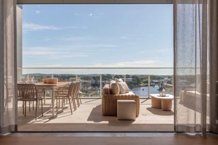 A luxurious apartment balcony with outdoor dining and lounge suite overlooking the Pumicestone Passage.