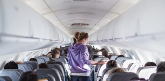 A woman walks down the aisle of a plane. Picture: Shutterstock.