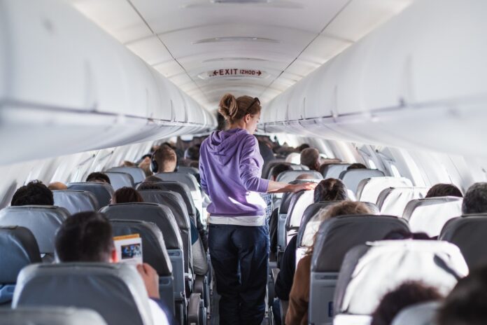 A woman walks down the aisle of a plane. Picture: Shutterstock.