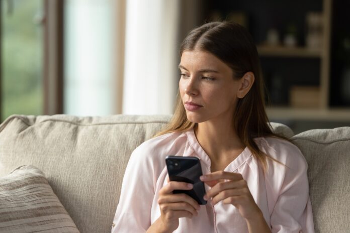 A young woman with a mobile phone, reflecting. Picture: Shutterstock.