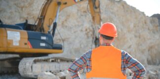 Worker in hardhat standing in stone quarry.