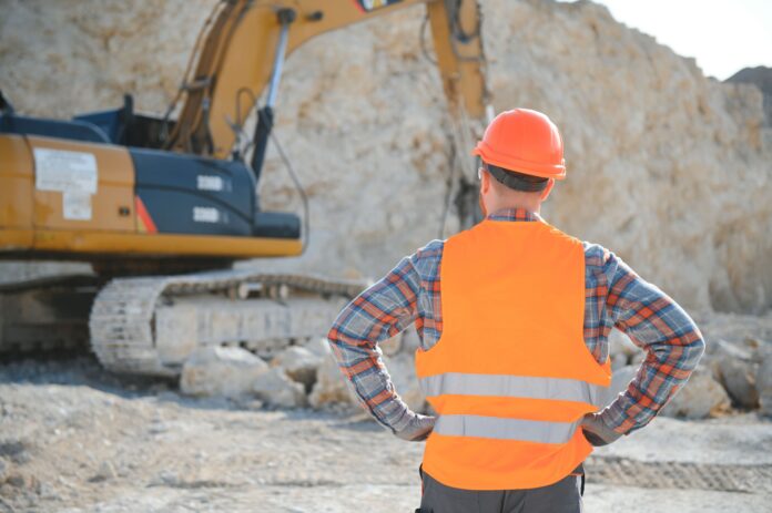 Worker in hardhat standing in stone quarry.