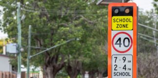A flashing speed limit sign near a school.