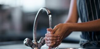 Hands washing under tap.