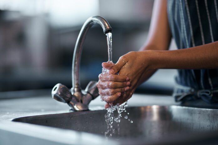 Hands washing under tap.