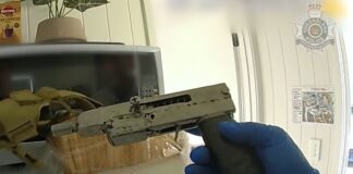 A detective holding a weapon that was seized.