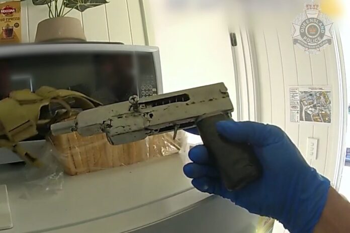 A detective holding a weapon that was seized.