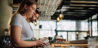 Staff clean glasses behind a bar.