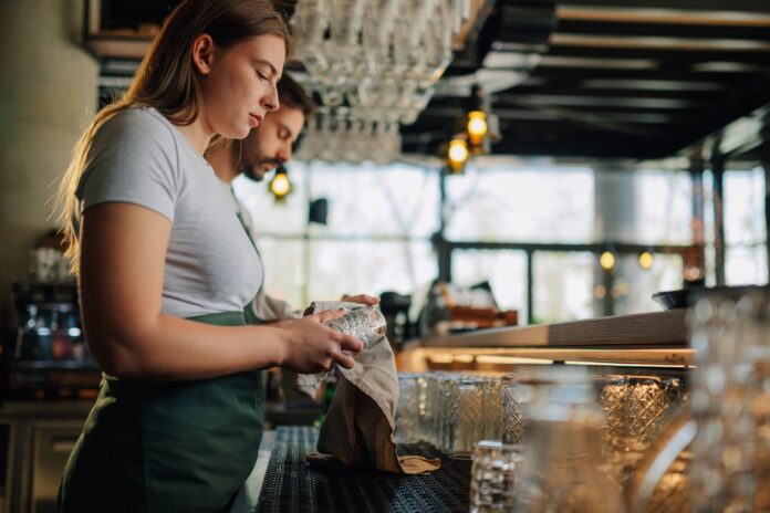 Staff clean glasses behind a bar.