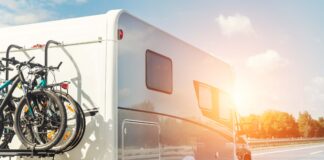 Scenic view big modern white family rv camper van vehicle driving on european highway road against blue sky in summer day. Rving motorhome lifestyle travel and adventure tourism trip journey concept