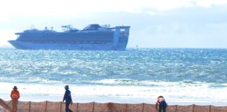 A fence being installed along Bribie Island, with a ship in the background.
