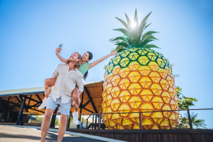 A couple takes selfie in front of the Big Pineapple.
