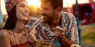 A couple share food outdoors as the sun sets.