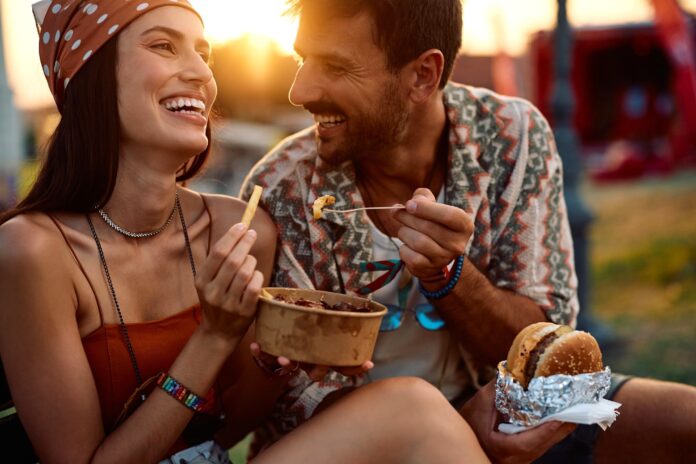 A couple share food outdoors as the sun sets.