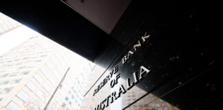 Reserve Bank of Australia name on black granite wall in Melbourne Australia with a reflection of high-rise buildings. The RBA building is located at 60 Collins St, Melbourne VIC 3000 Australia.