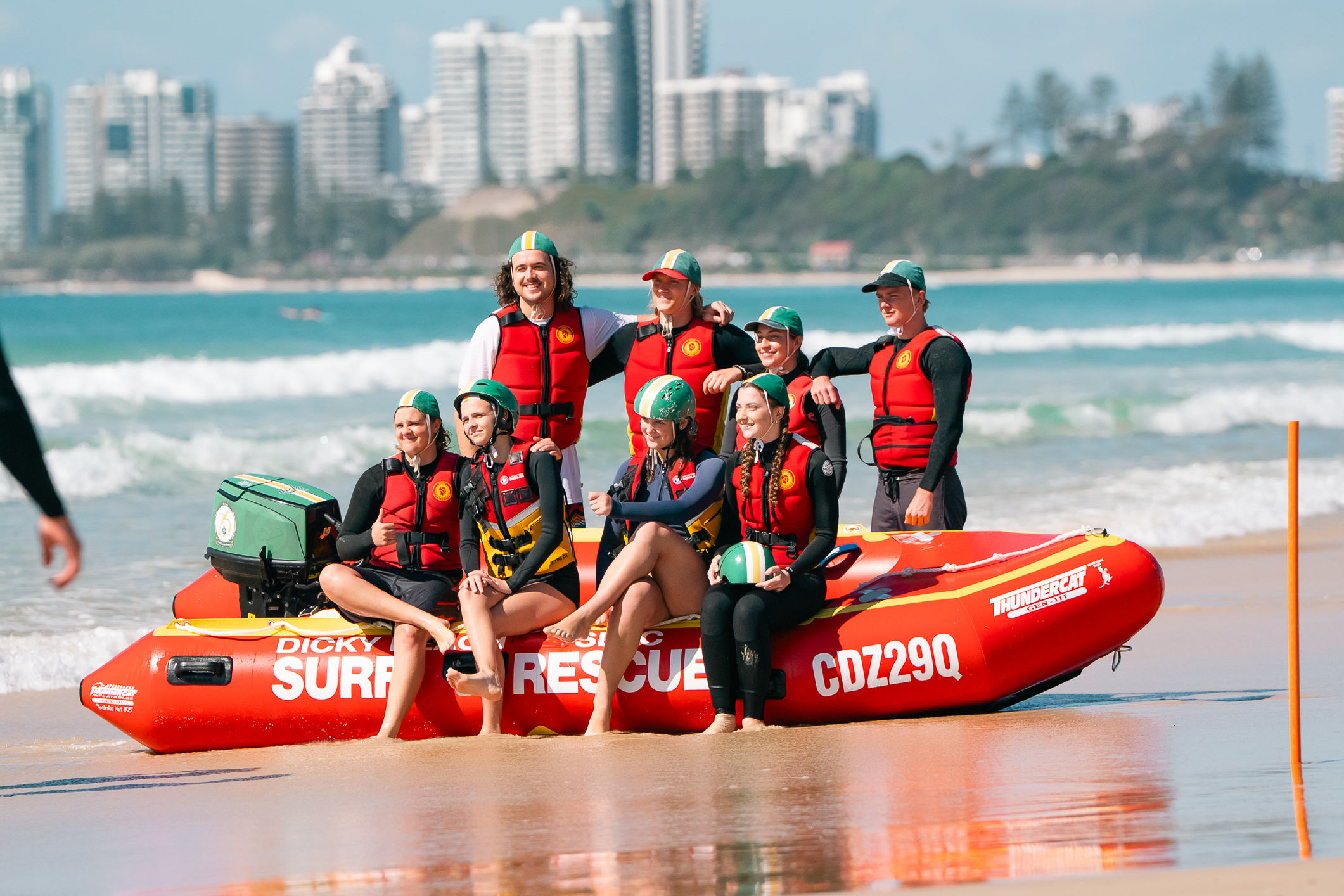 Dicky Beach SLSC IRB team members next to an inflatable rescue boat on the shoreline