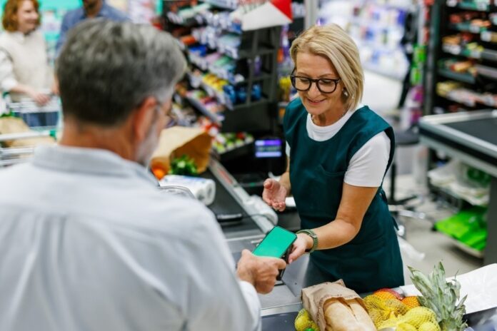 middle aged man paying for groceries shutterstock