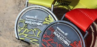 Finishers' medals on a sandy beach.