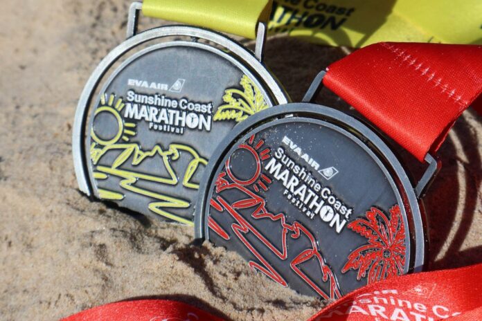 Finishers' medals on a sandy beach.