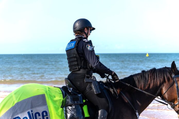 A police officer on horseback by the beach.