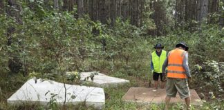 Two men clean old, dumped mattresses from bushland.