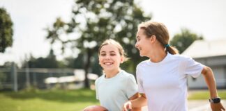 Two girls with a basketball on a court.