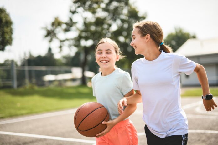 Two girls with a basketball on a court.
