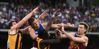 Brisbane Lions player Ty Gallop amid a pack of AFL players competing for the ball.