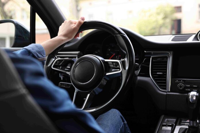 woman with one hand on steering wheel shutterstock