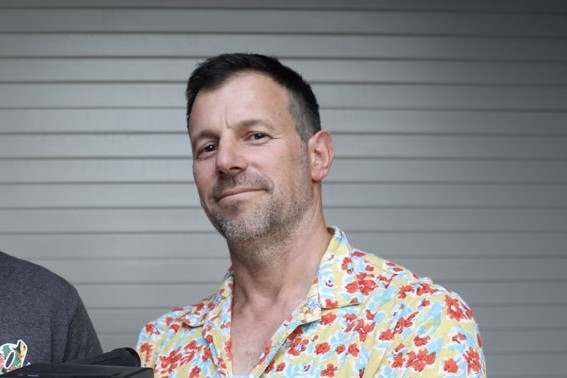 Headshot image of Jon Coghill wearing a floral print shirt.