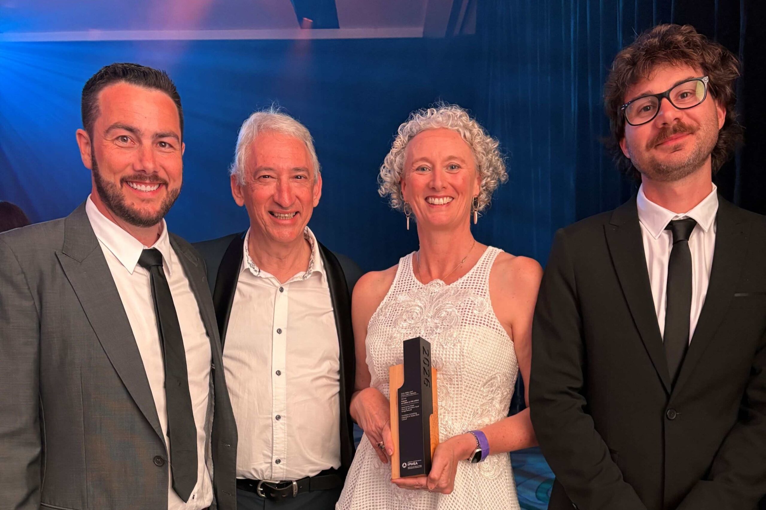 Four people dressed nicely at an event. The woman is holding a trophy.