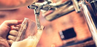 A hand is holding a beer glass and filling it with tap beer