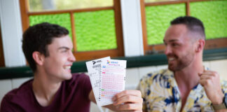 Two men smile and hold out Keno tickets.